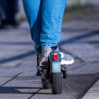 Füße und Beine eines Fahrers auf einem E-Scooter