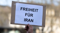 Eien Hand hält ein Schild hoch: "Freiheit für Iran"