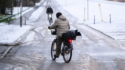  Eine Frau "schlittert" am Morgen mit ihrem Fahrrad über eine schneebedeckte glatte Straße