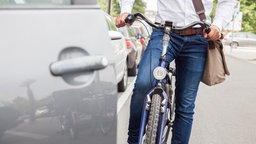 Ein Fahrradfahrer fährt beinahe gegen eine offene Autotür (Symbolbild).
