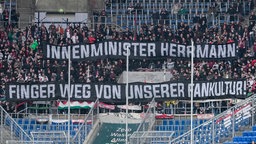 Die Fans vom FC Augsburg zeigen in der Fankurve ein Banner mit der Aufschrift: Innenminister Herrmann - Finger weg von unserer Fankultur.