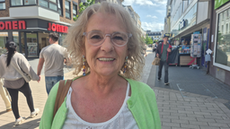 Eine Frau mit Brille und hellen Haaren in einer Einkaufsstraße.