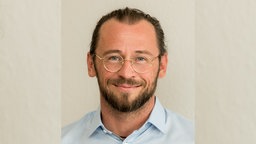 Ein Mann mit Brille lächelt in die Kamera