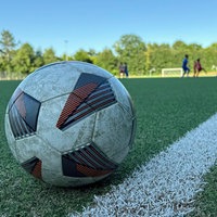 Fußball im Vordergrund - Jugendspiel im Hintergrund