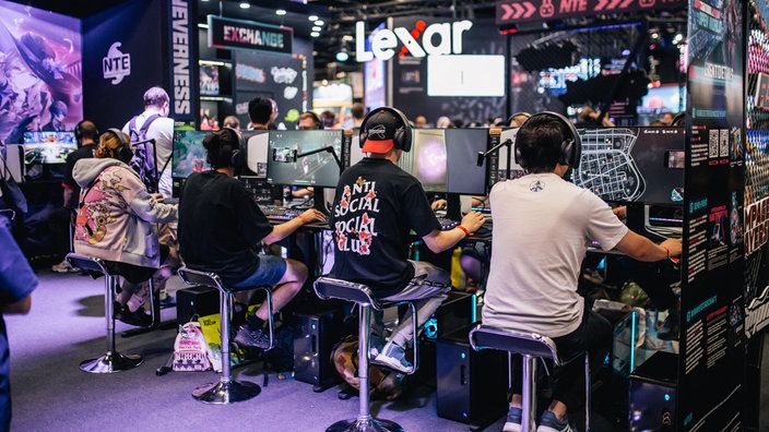 Besucher der Gamescom 2025 in Köln spielen Videospiele 