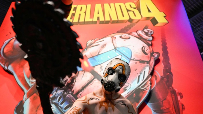 Ein Cosplayer posiert vor einem Plakat von Borderlands 4.