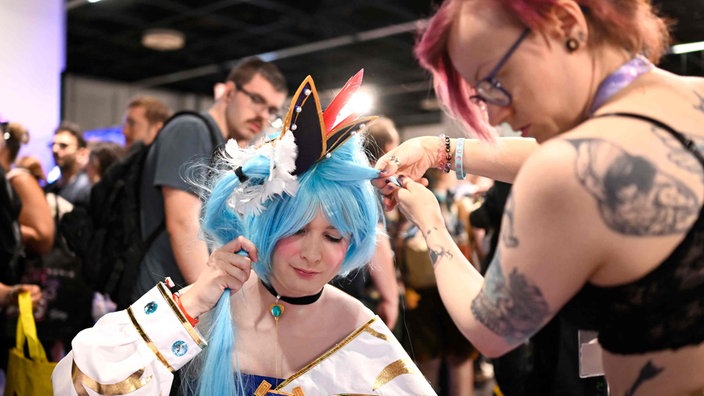 Ein Cosplayerin auf der Gamescom arbeitet an ihrer Frisur.