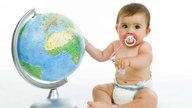 Ein Baby sitzt neben einem Globus.