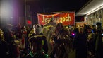 Verkleidete Menschen beim Geisterzug in Köln, vor einem Banner mit der Aufschrift "Jeisterzoch"
