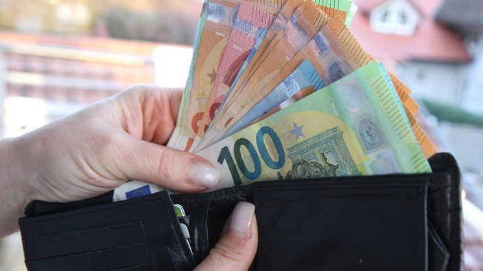 Eine Hand zieht Geldscheine aus einem Geldbeutel