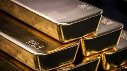 Goldbarren, die vor einem dunklen Hintergrund übereinander gestapelt sind