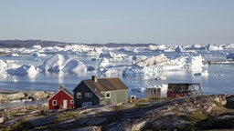 Bunte Holzhäuser mit Eisbergen im Hintergrund.