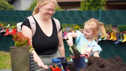 Lina Klein und ihre Mutter Sandra füllen Erde in die ausgedienten Gummistiefel, bevor die Blumen hinein kommen. 