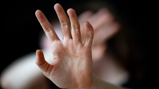 Eine Frau hält schützend ihre Hände vor das Gesicht