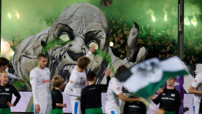 Die Spieler stehen vor der Choreografie der Fans mit einert Horrorfigur 