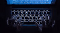 Ein Mann benutzt die beleuchtete Tastatur eines Notebooks