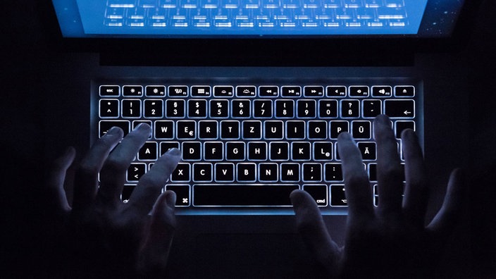  Ein Mann benutzt die beleuchtete Tastatur eines Notebooks