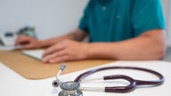 Ein Hausarzt sitzt in einem Sprechzimmer seiner Hausarztpraxis