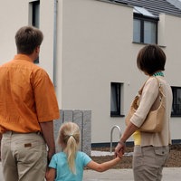 Junge Familie steht vor neugebautem Haus