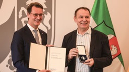 Hendrik Wüst und Jacques Tilly bei der Verleihung des Bundesverdienstordens