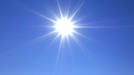 Eine strahlende Sonne vor blauem Himmel.