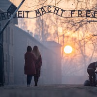 Besucher stehen am frühen Morgen am Tor zum früheren Konzentrationslager Auschwitz mit dem Schriftzug "Arbeit macht frei"