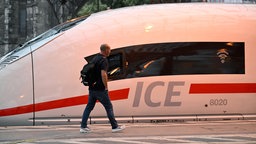 Ein Mann läuft an einem ICE-Zug der Deutschen Bahn vorbei, der im Kölner Hauptbahnhof steht.