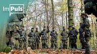 Soldaten der Bundeswehr stehen bewaffnet in einem Wald.