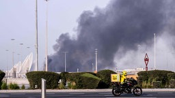 Straße mit Autos und einer Rauchwolke im Hintergrund 