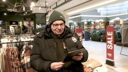 Joachim Hacker hält beim Einkaufen Tablet in der Hand