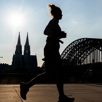 Eine Frau joggt am Kölner Rheinufer
