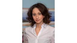 Ein brünette Frau mit einer Bluse im Portrait