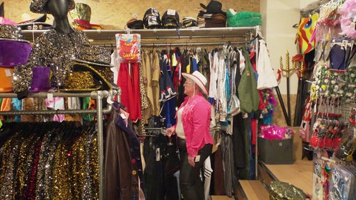 Eine Frau mit Cowboyhut steht in einem Kostümshop