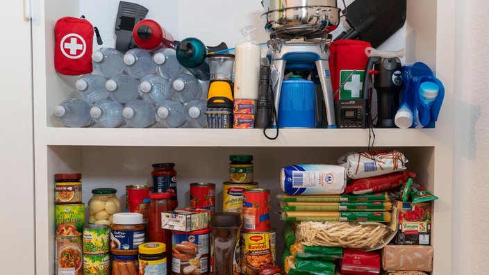 Wasser, Gaskocher und Lebenmittelvorräte in einem Schrank