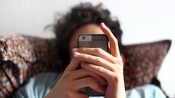 Ein junger Mann blickt auf ein Smartphone