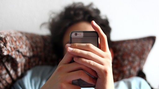 Ein junger Mann blickt auf ein Smartphone