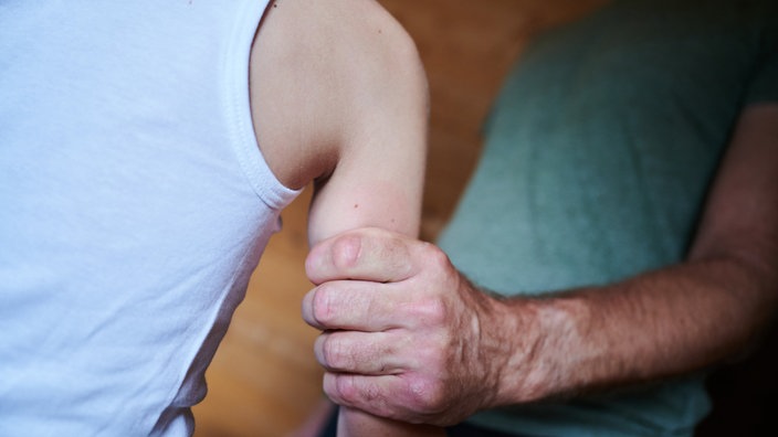 Ein Mann hält ein Kind fest am Arm