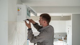 Ein Techniker repariert eine Klimaanlage in einer Wohnung