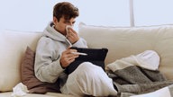 Kranke Person sitzt auf dem Sofa