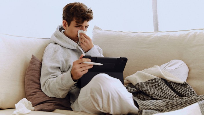 Kranke Person sitzt auf dem Sofa
