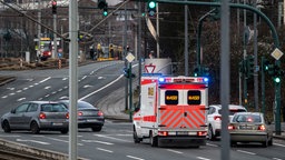 Rettungswagen im Einsatz mit Blaulicht und Martinshorn, an einer Ampelkreuzung, Fahrzeuge machen Platz für das Einsatzfahrzeug.