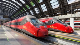 Zwei rote Züge von Italo stehen in einem Bahnhof. 