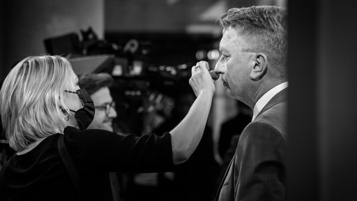 AfD-Vorsitzender Wagner wird geschminkt, im Hintergrund Kutschaty