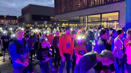 Menschen mit Stirnlampen warten auf den Startschuss des Rennens.