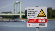 Ein Hinweisschild mit der Aufschrift "Achtung Lebensgefahr" weist am Rhein in Rodenkirchen auf die Gefahren beim Schwimmen in dem Fluss hin.