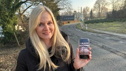 Anwohnerin in Haan-Gruiten zeigt ein Foto von dem Schlagloch in Lüdenscheid auf ihrem Handy