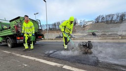 Zwei Männer arbeiten an Schlaglöcher auf einer Straße in Lüdenscheid