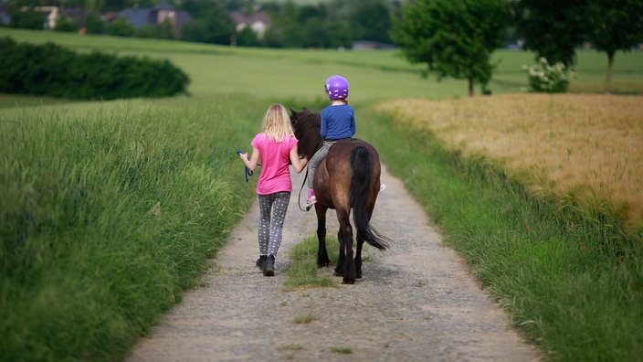 Ein Mädchen reitet mit dem Pony aus