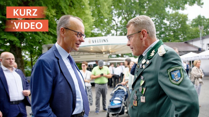 Friedrich Merz redet beim Schützenfest mit einem der Schützen