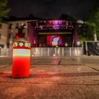 Auf dem Fronhof stehen am Abend vor einer Bühne drei einzelne Kerzen